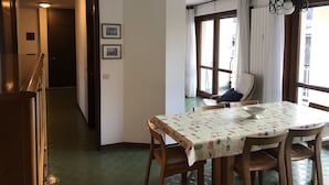 Ein Essbereich mit einem Tisch, der mit einer blumigen Tischdecke bedeckt ist, Holzstühle und einer Kristallleuchter.