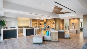 Un vestíbulo amplio con mostrador de recepción, zona de estar y cocina al fondo.