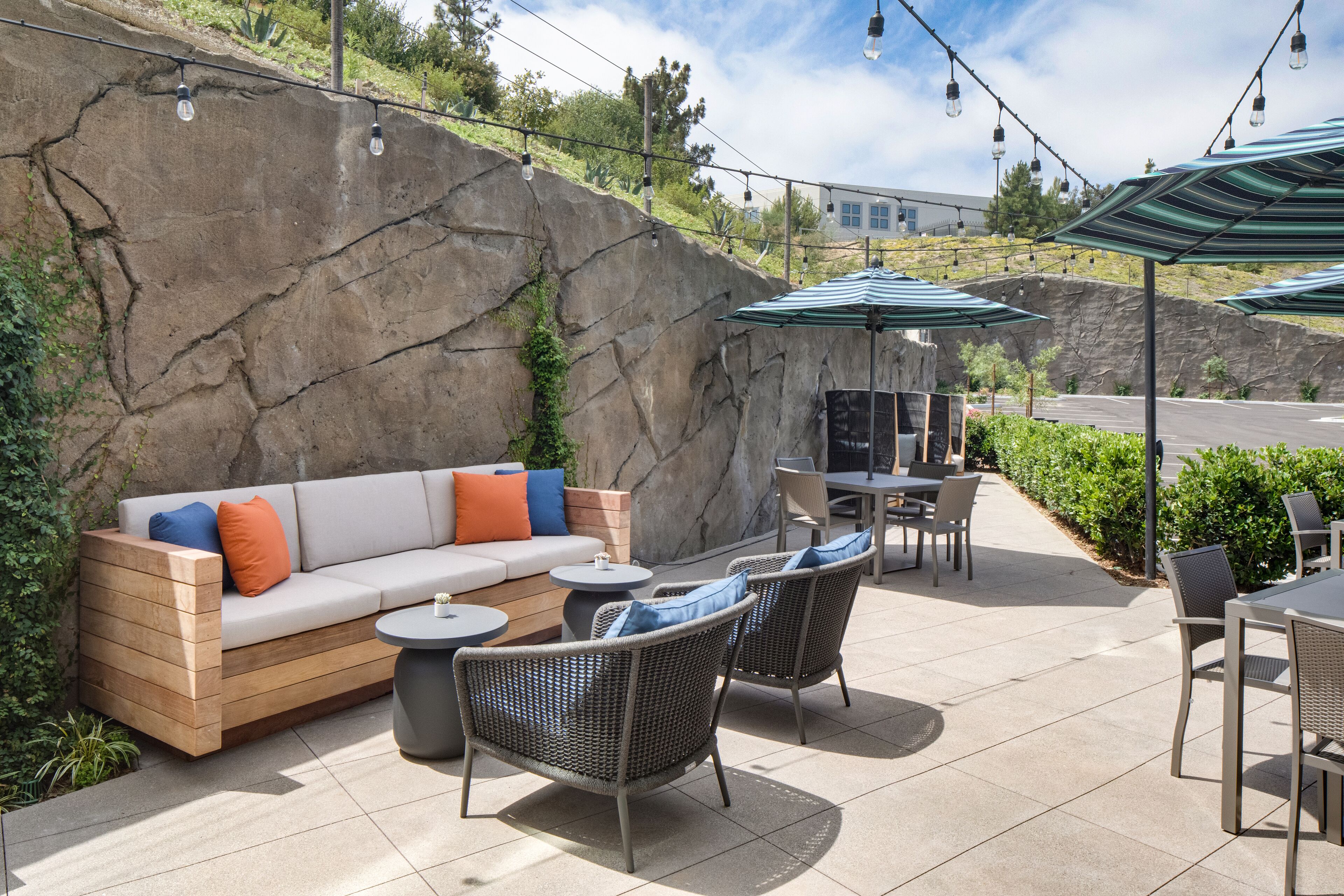 Eine Außenpatio-Terrasse mit einer Sitzecke, Stühlen, Tischen und Sonnenschirmen.