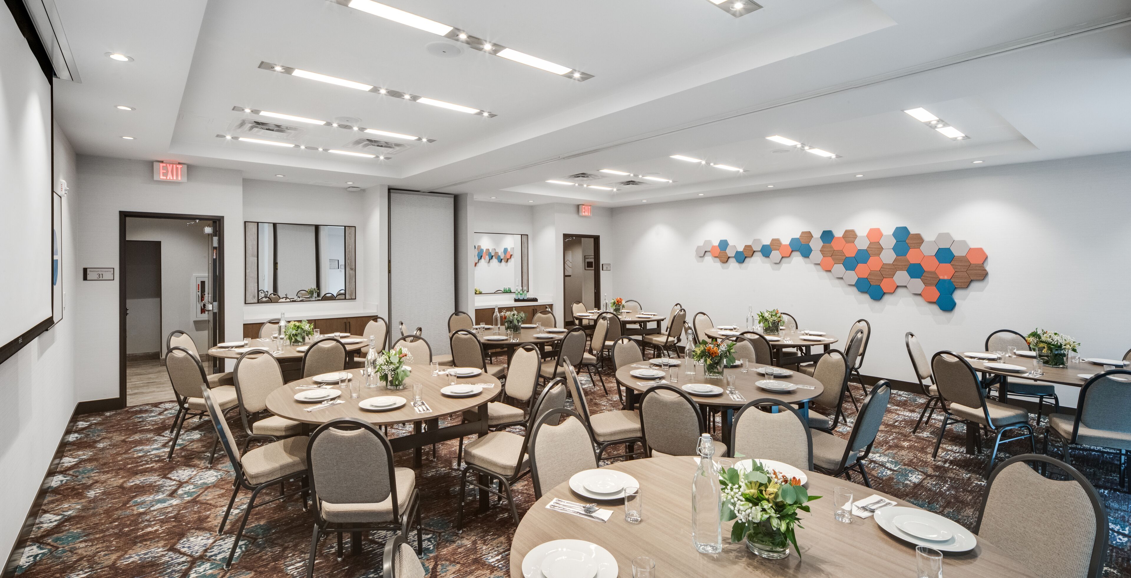 A conference room with multiple tables set for dining, equipped with chairs, plates, and glassware.