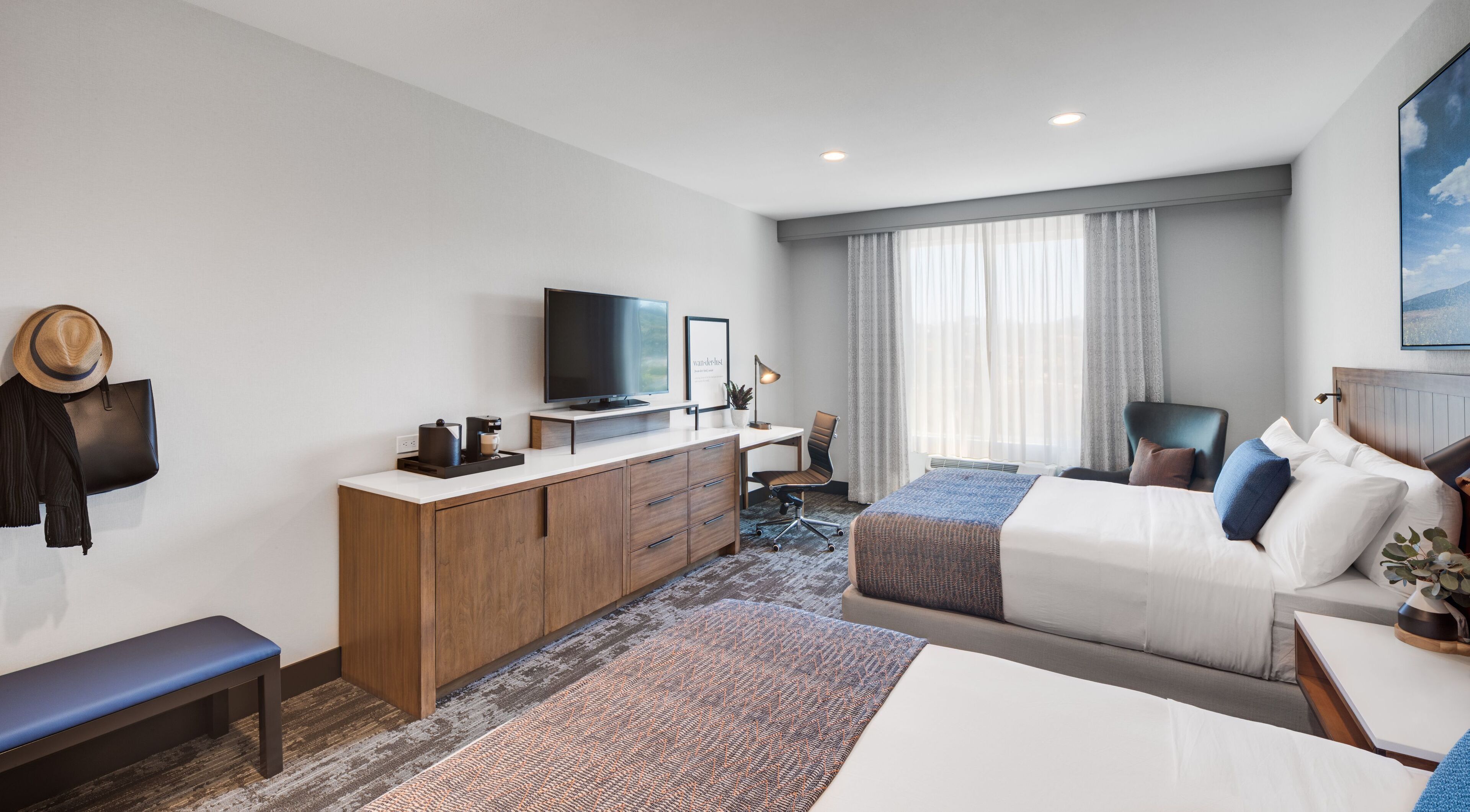 Una habitación de hotel moderna con una cama, un escritorio, un televisor y una zona de estar.