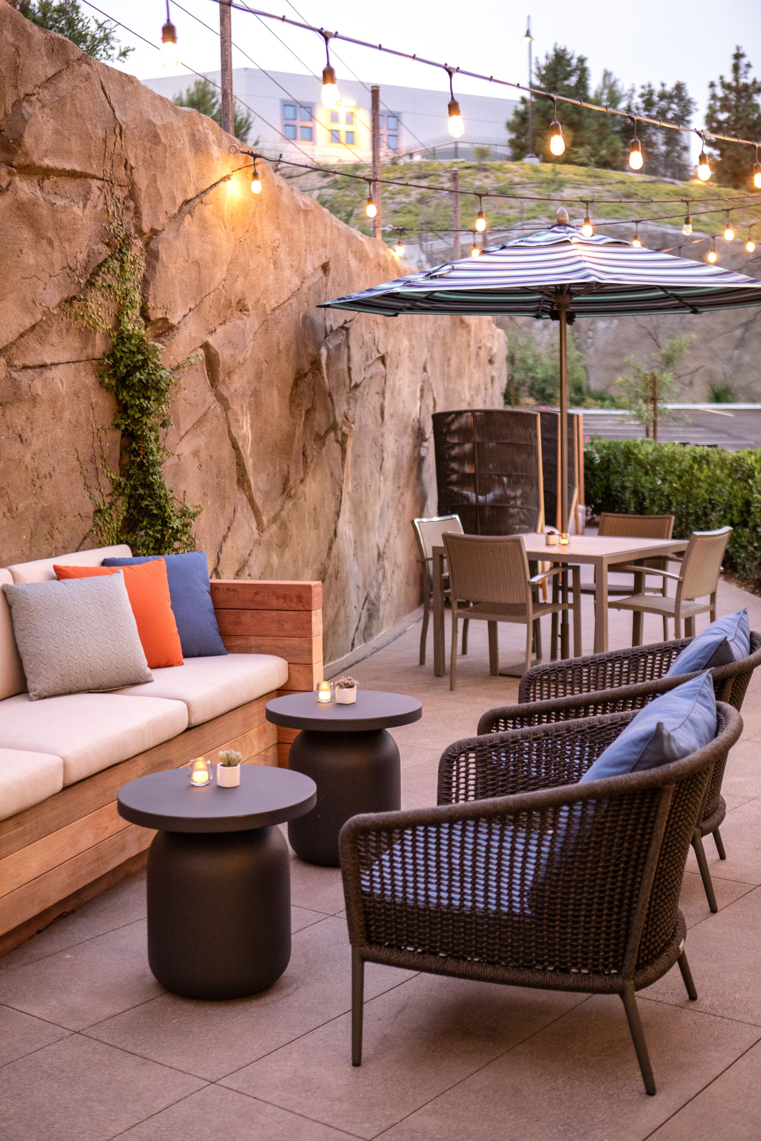 An outdoor patio with a sofa, chairs, a table, and an umbrella.