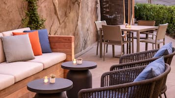 An outdoor patio with a sofa, chairs, a table, and an umbrella.