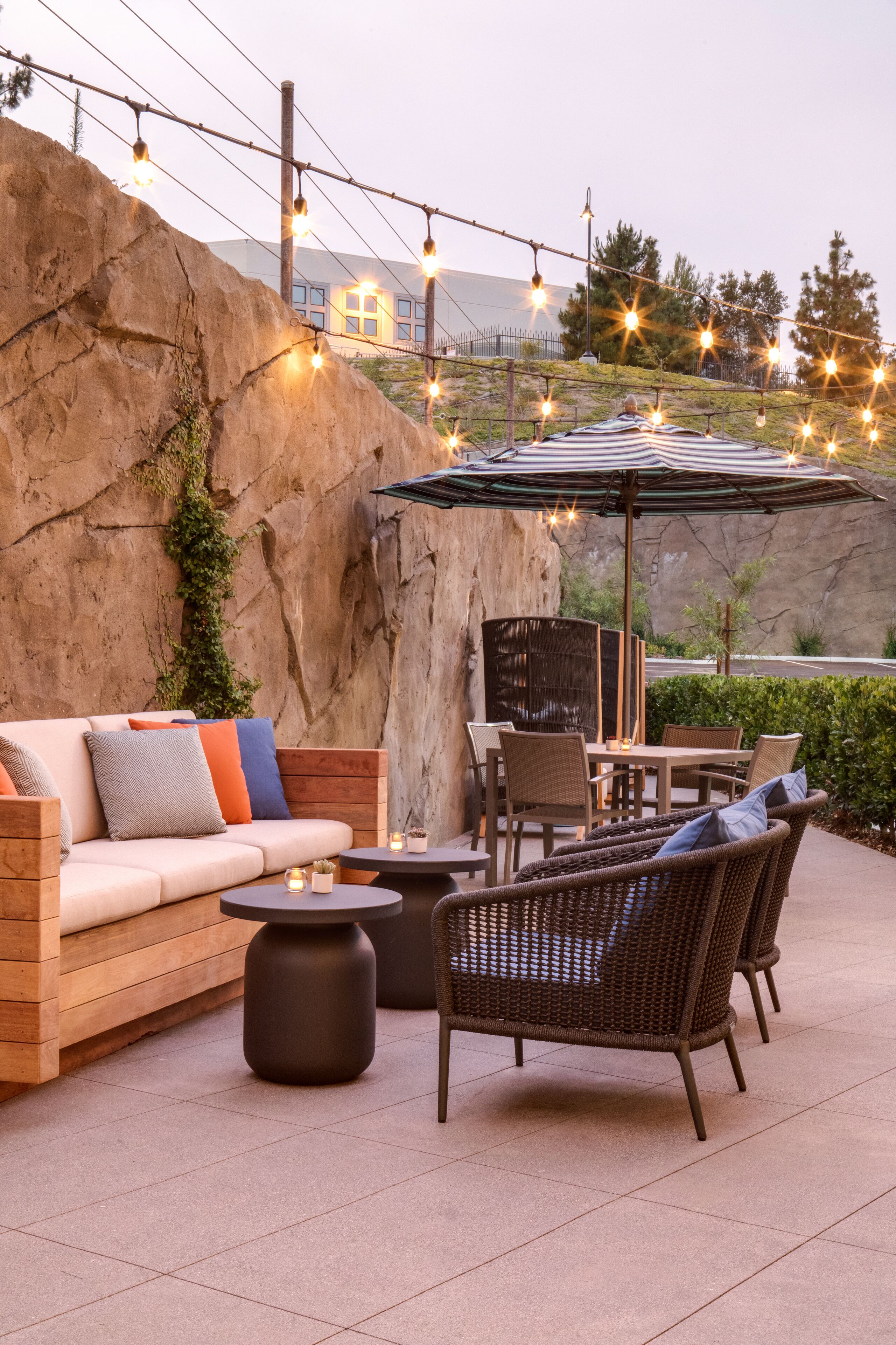 An outdoor patio with a sofa, chairs, a table, and string lights.