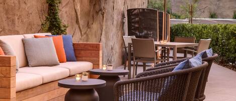 An outdoor patio with a sofa, chairs, a table, and string lights.