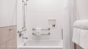 A modern bathroom with a bathtub, a shower, and a toilet. There is a towel rack with a towel and a small shelf with toiletries.