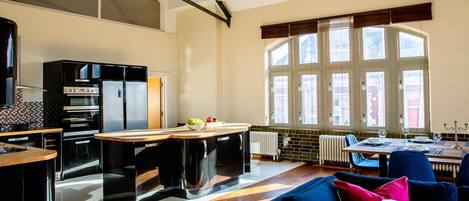 Een moderne keuken met een centraal kookeiland, ingebouwde apparaten en grote ramen.