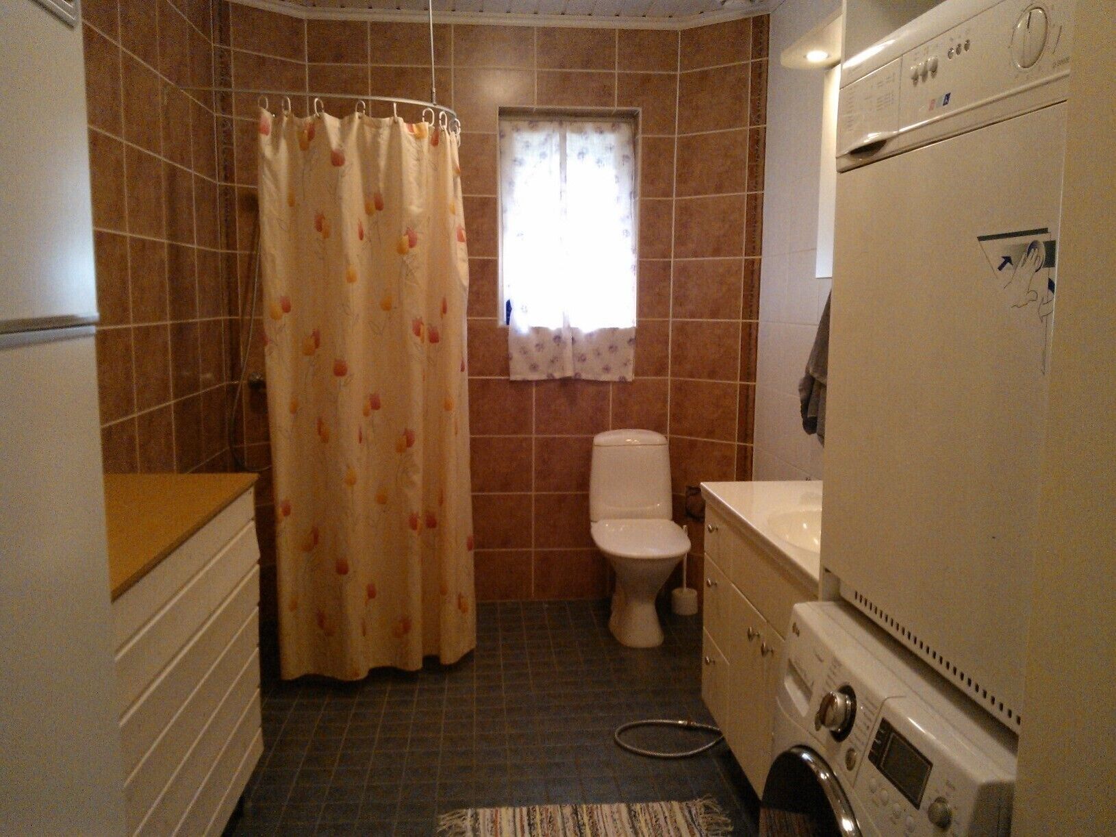 Un baño pequeño con cortina de ducha, inodoro y lavadora.