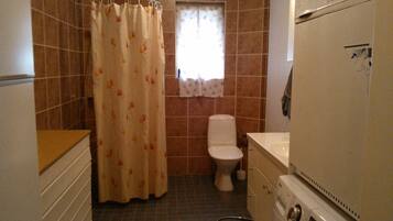 Un baño pequeño con cortina de ducha, inodoro y lavadora.