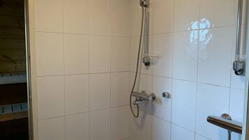 A shower with a handheld showerhead and a wall-mounted faucet.