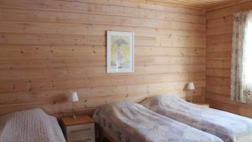 A wooden-paneled room with two beds, a nightstand with a lamp, and a framed picture on the wall.