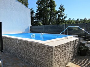 Swimmers can enjoy a refreshing dip in the pool surrounded by a stone wall with a textured pattern.