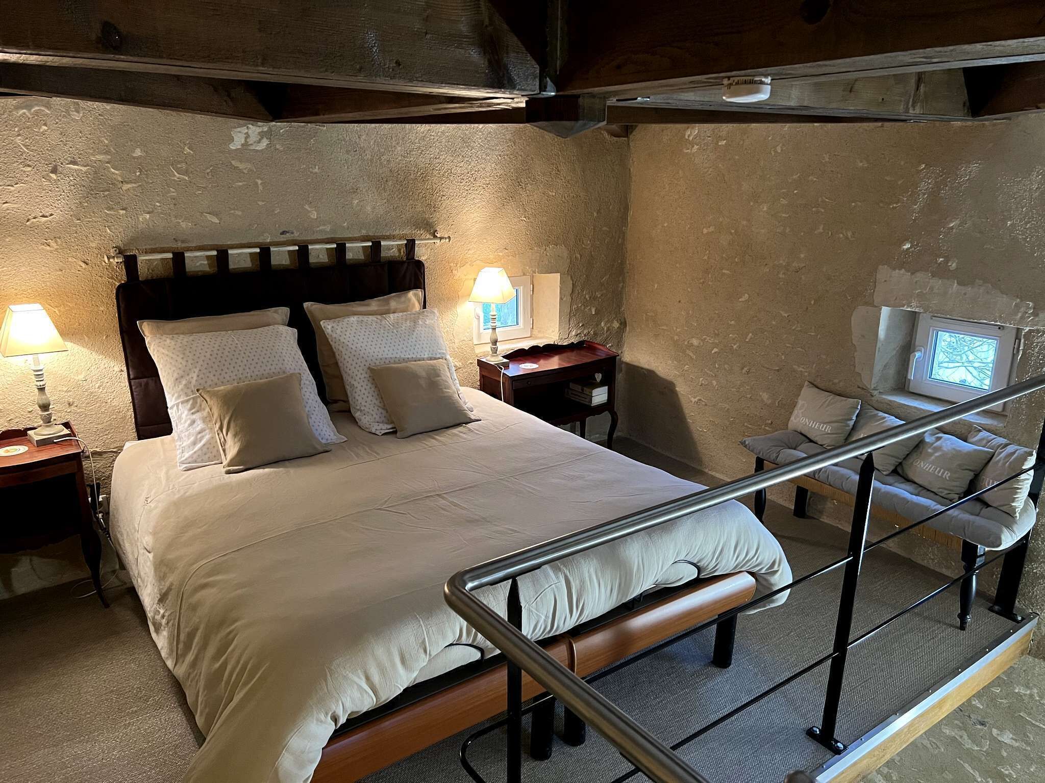 A bedroom with a bed, bedside tables, a TV, and a staircase.