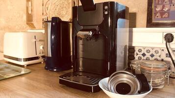 Una cocina con cafetera, tostadora y un bol con tapa.