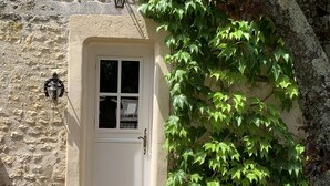 A white door with a small window, a bell, and a wall-mounted light fixture. - Gites de Gondières (Saint-Eloi)