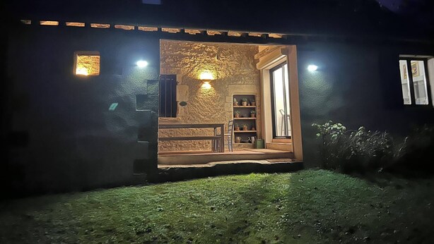 A building with a stone facade, a wooden door, and a small porch with a ladder. - Gites de Gondières (Saint-Eloi)