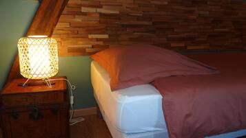 A bed with a wooden headboard, a nightstand with a lamp, and a power outlet.