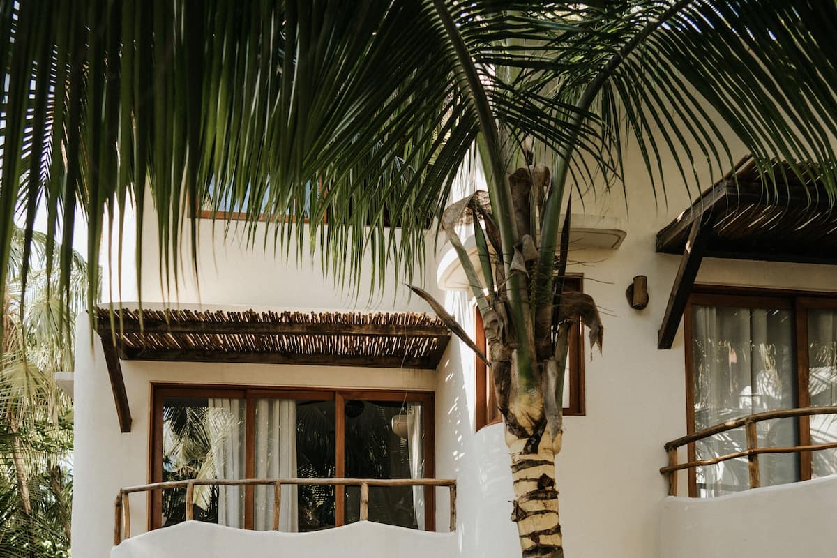 A two-story building with balconies, surrounded by lush tropical vegetation.