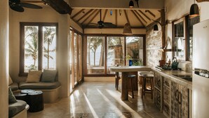A spacious kitchen with large windows, a dining area, and a seating nook with a view of the ocean. - Zorba Tulum Beach Homes (Tulum)