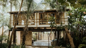 A two-story building with a wooden balcony, surrounded by lush tropical vegetation. - Zorba Tulum Beach Homes (Tulum)