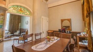 A dining area with a wooden table, chairs, a chandelier, and a stained glass window. - Entire Historical Bed and Breakfast in Rico, Cololorado (Rico)