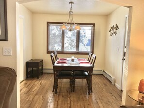 A dining room with a wooden table, chairs, and a window with blinds.