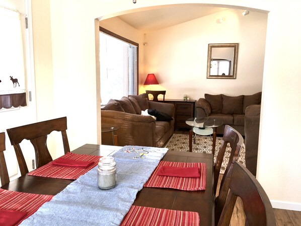 A living room with a dining table, two couches, a small side table, and a lamp.