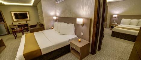 A hotel room with a large bed, bedside tables, a TV, and a bathroom visible through an open door.