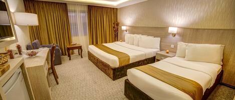 A hotel room with two beds, a desk, a chair, a lamp, and a nightstand.
