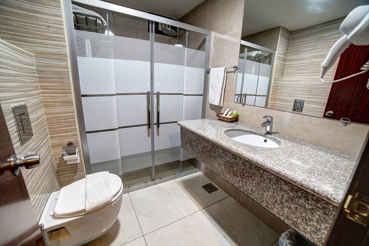 deluxe single room | bathroom | shower, rainfall showerhead, free toiletries, hair dryer