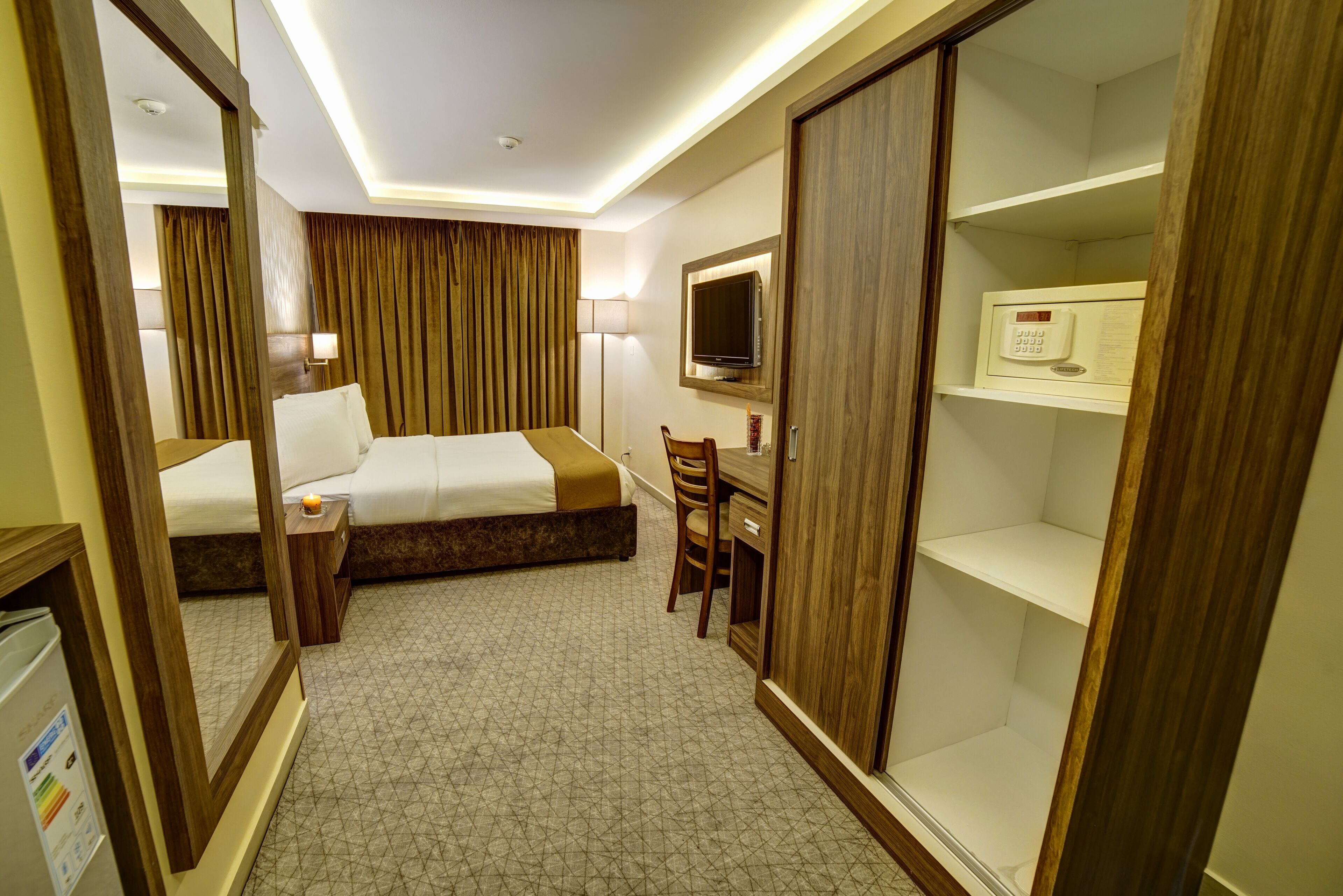 A hotel room with a bed, a desk, a chair, a TV, a microwave, and a wardrobe.