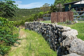 A stone wall leading to a wooden gate with a sign that reads 'ANTLER RUN RANCH.'