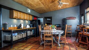 A kitchen with wooden cabinets, a black refrigerator, and a dining area with a round table and chairs.