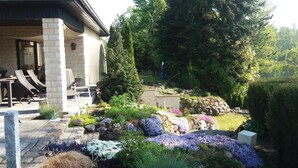 Un jardin doté d’un espace patio, de murs en pierre et de différentes espèces de plantes.