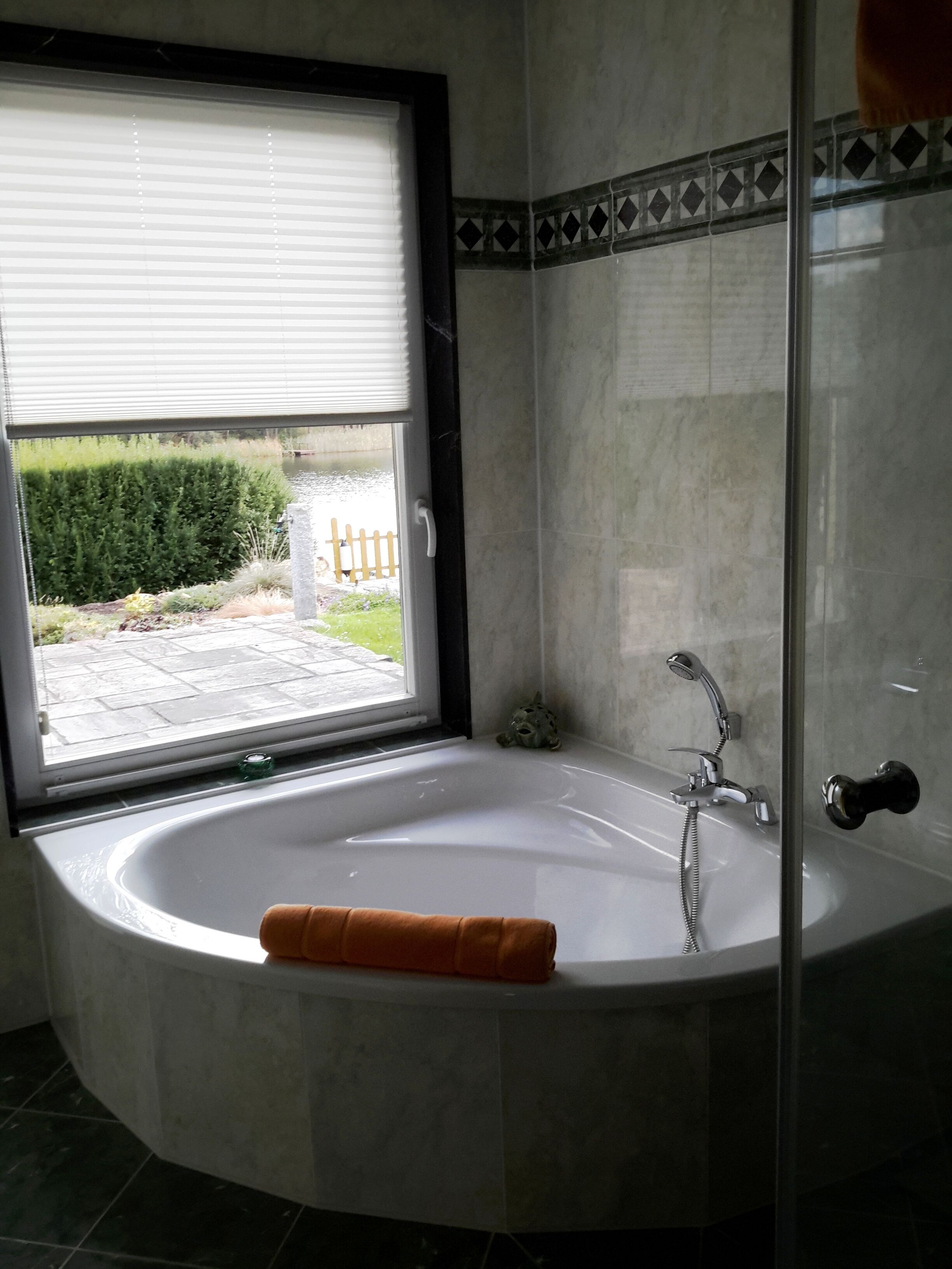 A bathroom with a bathtub, a shower, and a window with blinds.