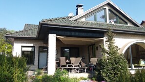 A two-story house with a covered porch, outdoor seating, and a garden.