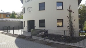 Een gebouw met de naam "Karola" op de gevel, uitgevoerd in moderne architectuur met een gebogen dak en meerdere ramen.