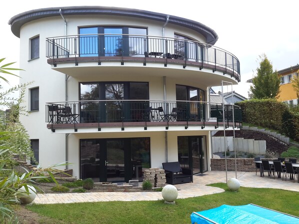 A two-story residential building with a balcony, outdoor seating, and a swimming pool. - Haus Karola (Wendisch Rietz)