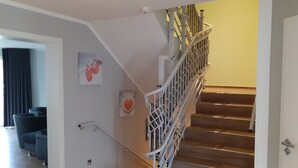 Een trap met witte leuningen en houten treden die uitkomt op een plateau.