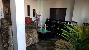 A living room with a sofa, a coffee table, a TV, and a plant. - Daily Apartment in Iquique in my house. (Iquique)