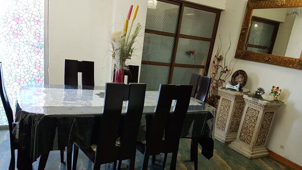 A dining area with a glass table, black chairs, and a decorative vase with flowers. - Daily Apartment in Iquique in my house. (Iquique)