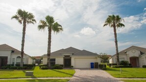 A residential area with three houses, each with a garage, surrounded by well-maintained lawns and palm trees. - Casablanca Villaview by Orlando Short Term (Kissimmee)
