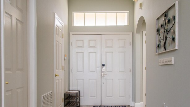 A hallway with two white doors, a vent, a small black crate, and a framed artwork on the wall. - Casablanca Villaview by Orlando Short Term (Kissimmee)