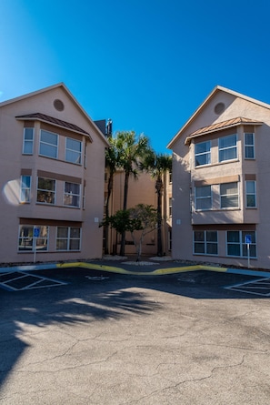 A two-story building with a flat roof, large windows, and a parking lot in front.