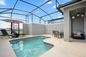 Ein Swimmingpool mit Liegestühlen und einem Tisch, umgeben von einer überdachten Terrasse mit hängenden Pflanzen.