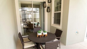 A round dining table with wicker chairs and potted plants. - Gatsby Storey by Orlando Short Term (Kissimmee)