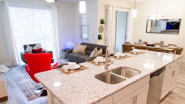 A modern kitchen with granite countertops, a double sink, and a dishwasher. - Gatsby Storey by Orlando Short Term (Kissimmee)