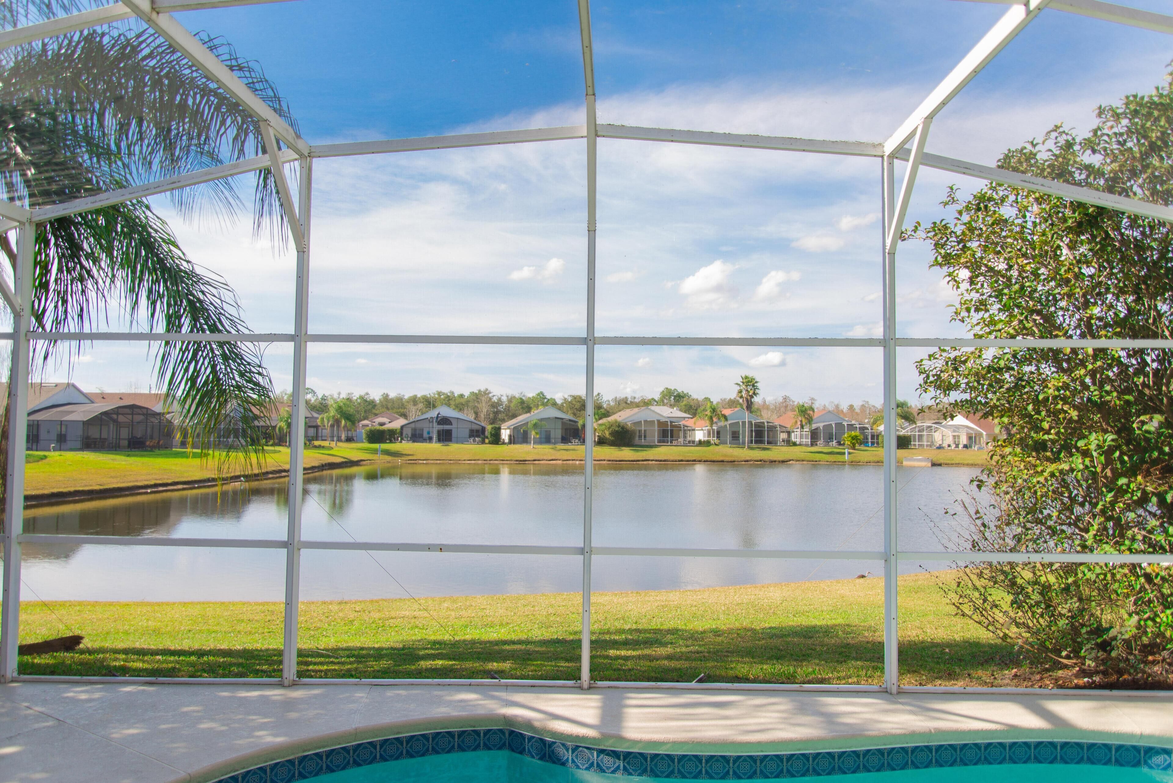 A pool area with a view of a lake and houses in the background.