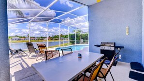A covered outdoor area with a pool, a barbecue grill, and a table with chairs. - Paradise Island by Orlando Short Term (Kissimmee)