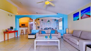 A spacious living room with a white coffee table, beige sofa, and a blue accent wall. - Paradise Island by Orlando Short Term (Kissimmee)